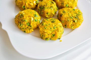 Tasty yellow falafel on the white plate.