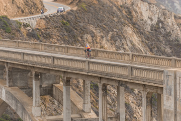 Cyclist over the Bixby Creek Bridge at sunset in Big Sur, California, USA
