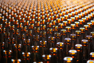 Glass bottle texture. Glass bottle at factory for production of glass containers. Many of transparent brown glass bottle into row, close up.