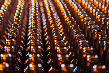 Glass bottle texture. Glass bottle at factory for production of glass containers. Many of transparent brown glass bottle into row, close up.