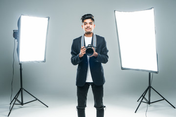 Young indian man photographer taking photo with professional digital camera, focus on hand and lens...
