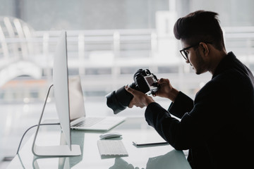 Professional photographer man with camera and laptop computer in office