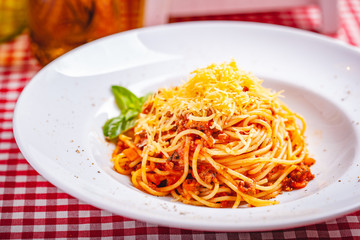 Italian cuisine. Spaghetti bolognese with meat, parmesan cheese and tomatoes on white plate. Close up