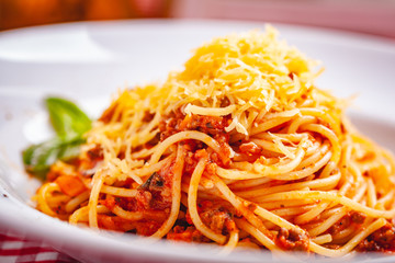 Italian cuisine. Spaghetti bolognese with meat, parmesan cheese and tomatoes on white plate. Close up