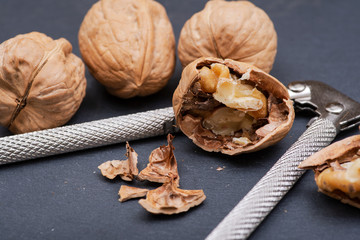 Brown premium raw organic walnuts and nutcracker in wooden bowl on natural stone background