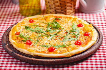 Pizza Margherita (Margarita) with fresh arugula on wooden board. Close up