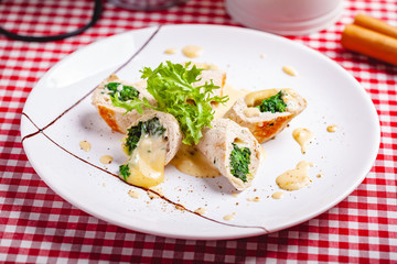 Steamed chicken cutlets stuffed with spinach on white plate. Close up
