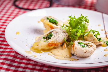 Steamed chicken cutlets stuffed with spinach on white plate. Close up
