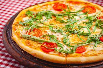 Pizza Margherita (Margarita) with fresh arugula on wooden board. Close up