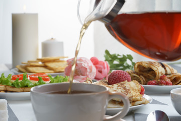 Fresh, tasty breakfast with a sandwich and tea on a light background.