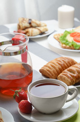 Fresh, tasty breakfast with tea and buns on a light background.