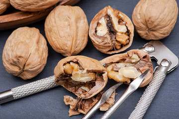 Brown premium raw organic walnuts and nutcracker in wooden bowl on natural stone background