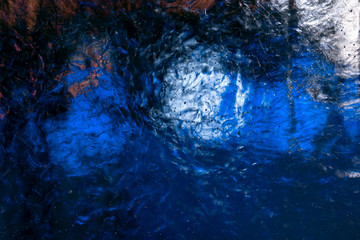 Clear transparent ice with small bubbles illuminated with white and blue light. The structure of the ice creates fantastic patterns.