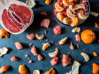 Orange slices and red pomelo scattered on a dark background. Fruit pattern. Abstract food background