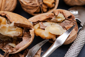 Brown premium raw organic walnuts and nutcracker in wooden bowl on natural stone background