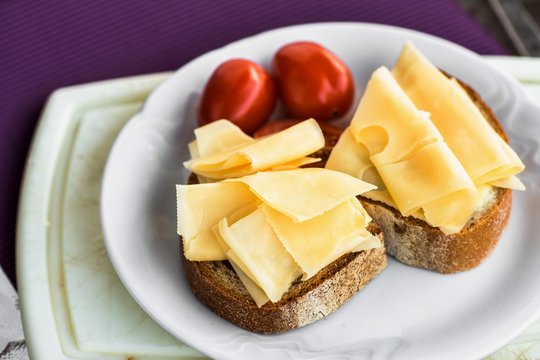 Snack with sliced cheese, bread and tomato.