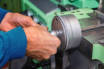 Mens hands on a cross feed handwheel of lathe machine