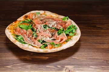 Pizza with ham and vegetables on wooden table