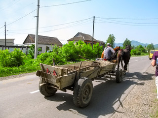 Ukraine, Khust - May 1, 2018: A cart pulled by two horses rides on a paved rural road in Khust....