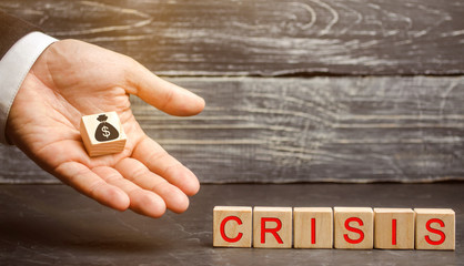 Businessman holds in his hands a cube with the image of the dollar and the word crisis. Fall...