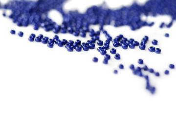 Dark blue seed beads scattered on a white surface close up