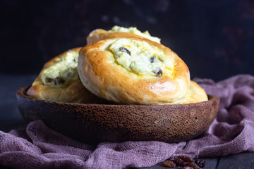 Fresh homemade open patties with cottage cheese and raisins. Traditional Russian yeast pastry vatrushka, round buns, curd tart. Buns with cottage cheese and raisins. Rustic style. Copy space.