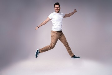Fototapeta na wymiar handsome man casual dressed celebrating and jumping on gray background