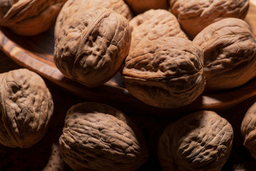 Brown premium raw organic walnuts in wooden bowl on cork background.