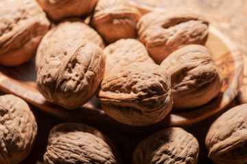 Brown premium raw organic walnuts in wooden bowl on cork background.