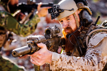 rangers with assault rifles on battlefield background. army, military and people concep