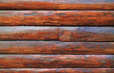 Dark brown wood log wall of an aging log cabin for texture, background or banner