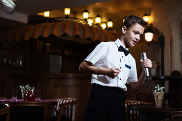 Boy in a white shirt singing into the microphone in a restaurant. baby karaoke.