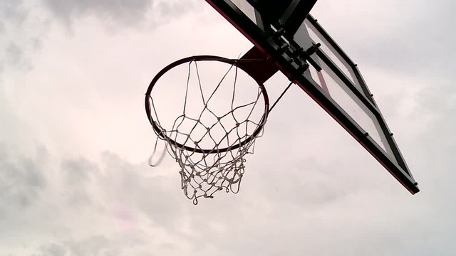 the ball flies through the basketball Hoop on the background of the grey sky