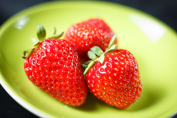 Sweet fresh strawberries on a green plate.