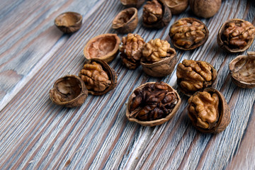  Walnuts are on a wooden surface.  Walnuts are shelled. The edible kernel of nut is in a shell.