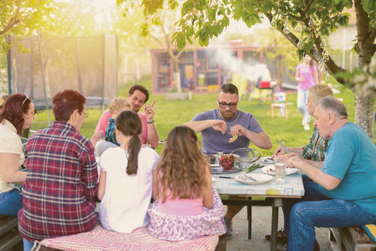 Picture of big happy family having lunch in their backyard. Spending time together on sunny summer day and having fun.