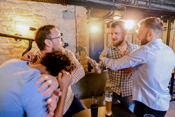 Man stopping his friend to get in a bar fight. Group of man drinking in a bar and fighting.