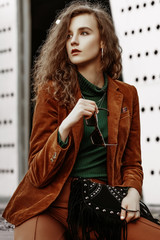 Outdoor fashion portrait of young confident fashonable woman wearing brown corduroy blazer,...