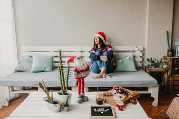 .Sweet and cheerful woman enjoying christmas at her home. Wearing christmas costume, having fun and eating tipical sweets. Lifestyle. Season photography.
