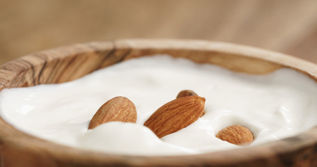 Closeup   of homemade yogurt with almonds in wood bowl on wooden table