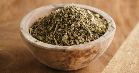 Closeup   of dried provence herb mix in wood bowl for seasoning on table