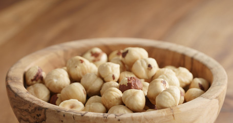 Closeup   of roasted hazelnuts in wood bowl on wooden table