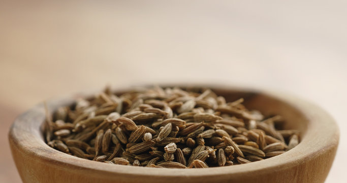 Closeup   of cumin zira seeds in wood bowl on table