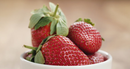 Closeup   of fresh strawberries in bowl on wood table