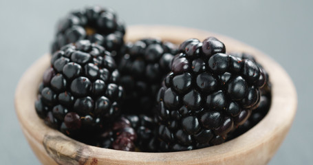 Closeup   of ripe organic blackberries in wood bowl on slate background