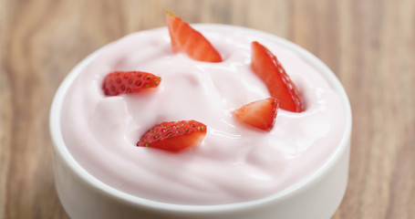 Closeup   of organic strawberry yogurt on wooden table