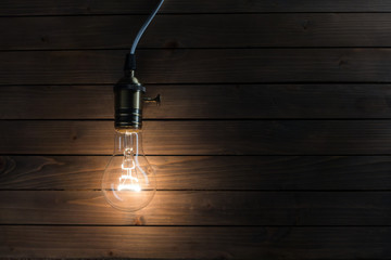 The light bulb illuminates on wooden background