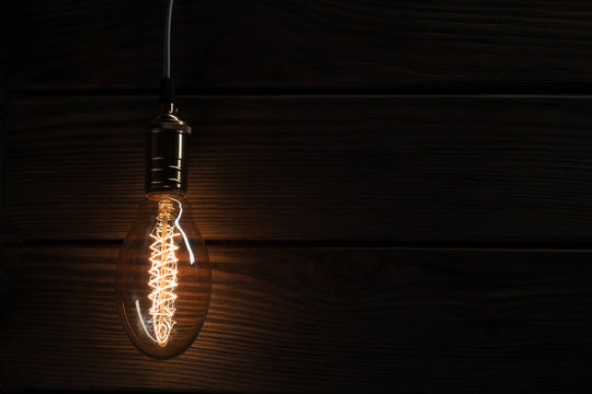 The light bulb illuminates on wooden background