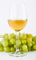 A glass of white wine with a bunch of green grapes on a white background. Alcoholic beverages.