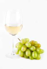 A glass of white wine with a bunch of green grapes on a white background. Alcoholic beverages.